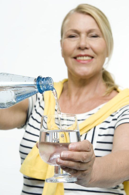 Best-Agerin schenkt Mineralwasser ein