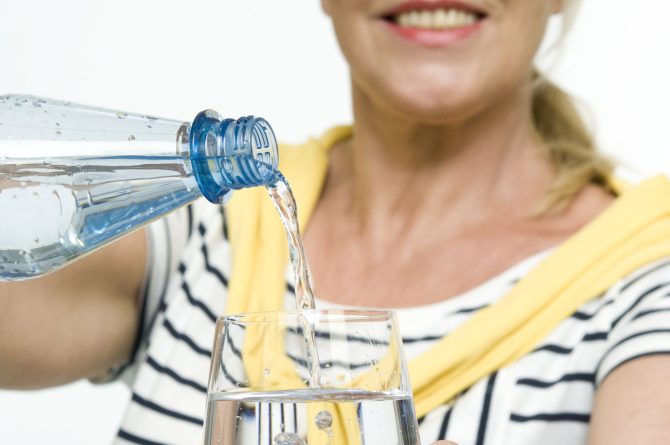Best Agerin schenkt Mineralwasser ein